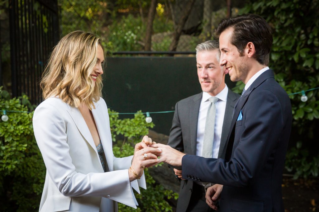 Bride giving groom ring during ceremony for an article on how to modernize your wedding