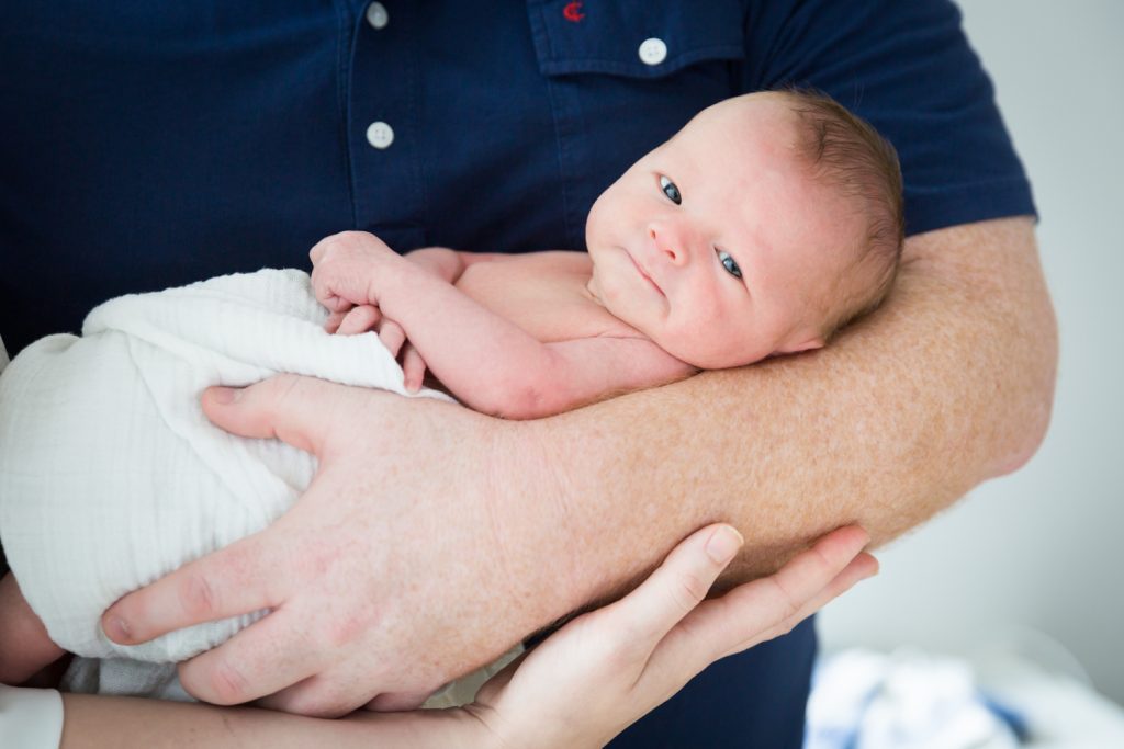 Close up of newborn baby held by father