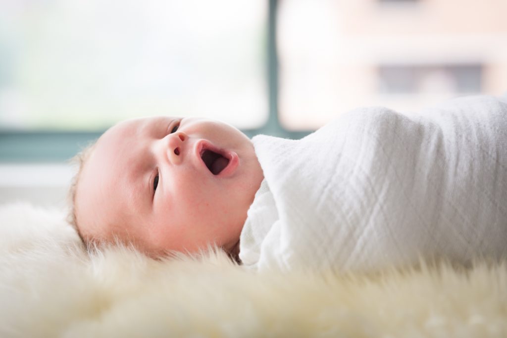 Newborn baby yawning while swaddled