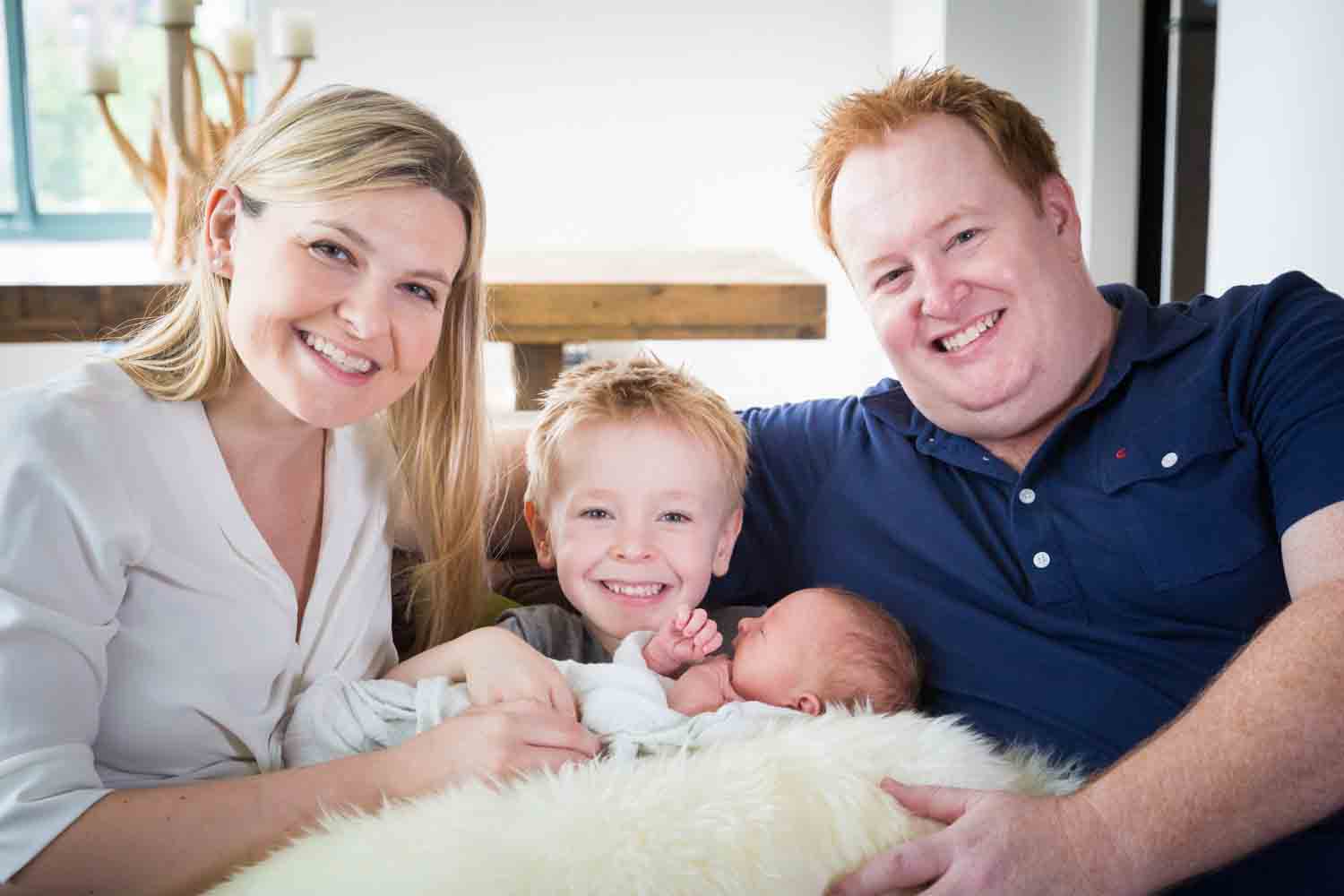 Parents and little boy holding newborn on couch