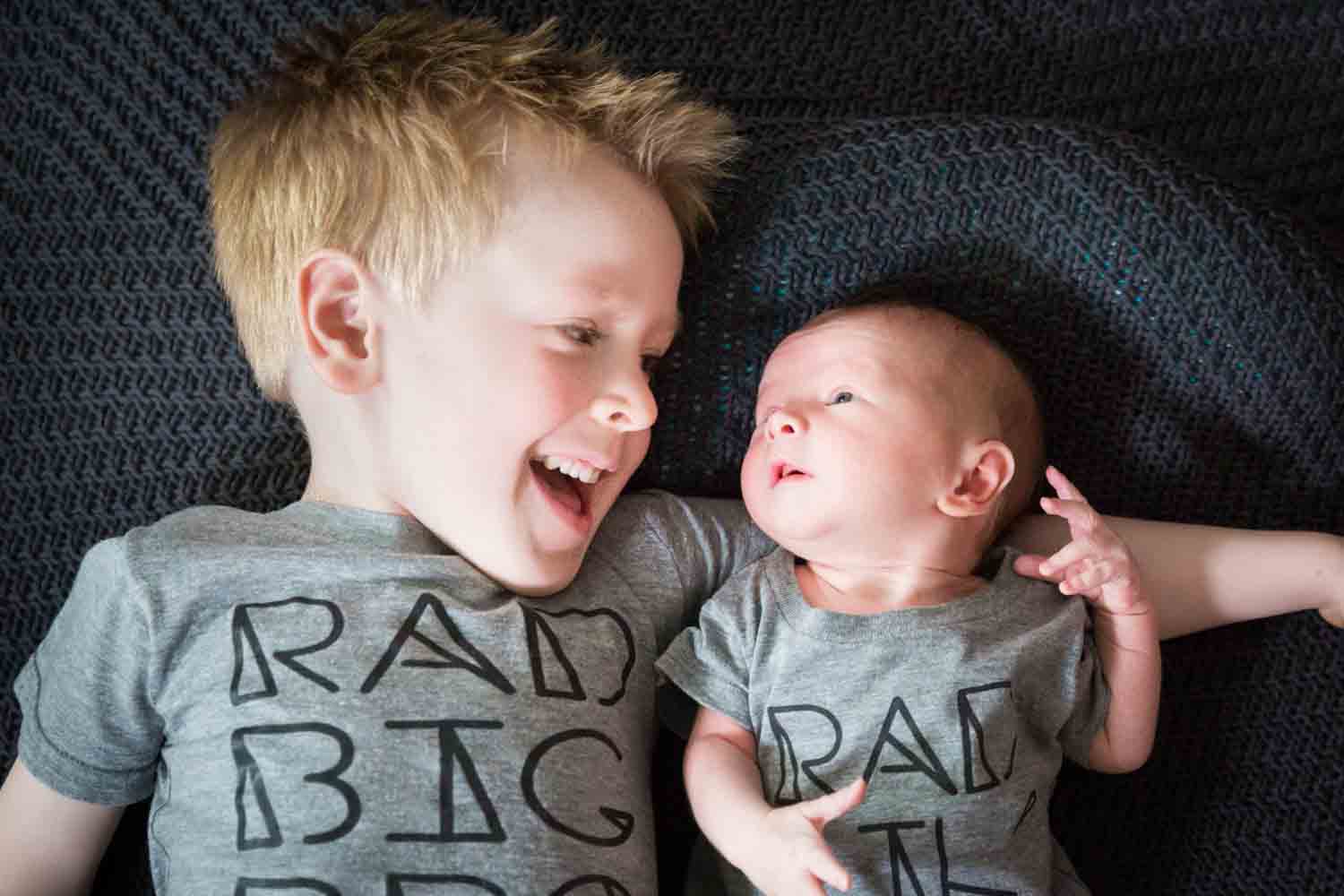 Little boy looking at newborn baby and wearing similar t-shirts