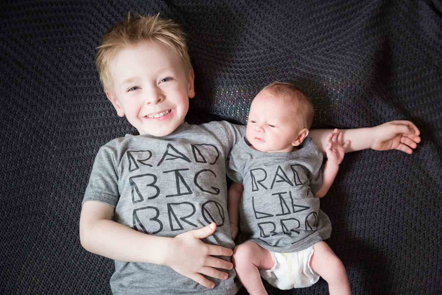 Little boy and newborn baby wearing matching grey t-shirts
