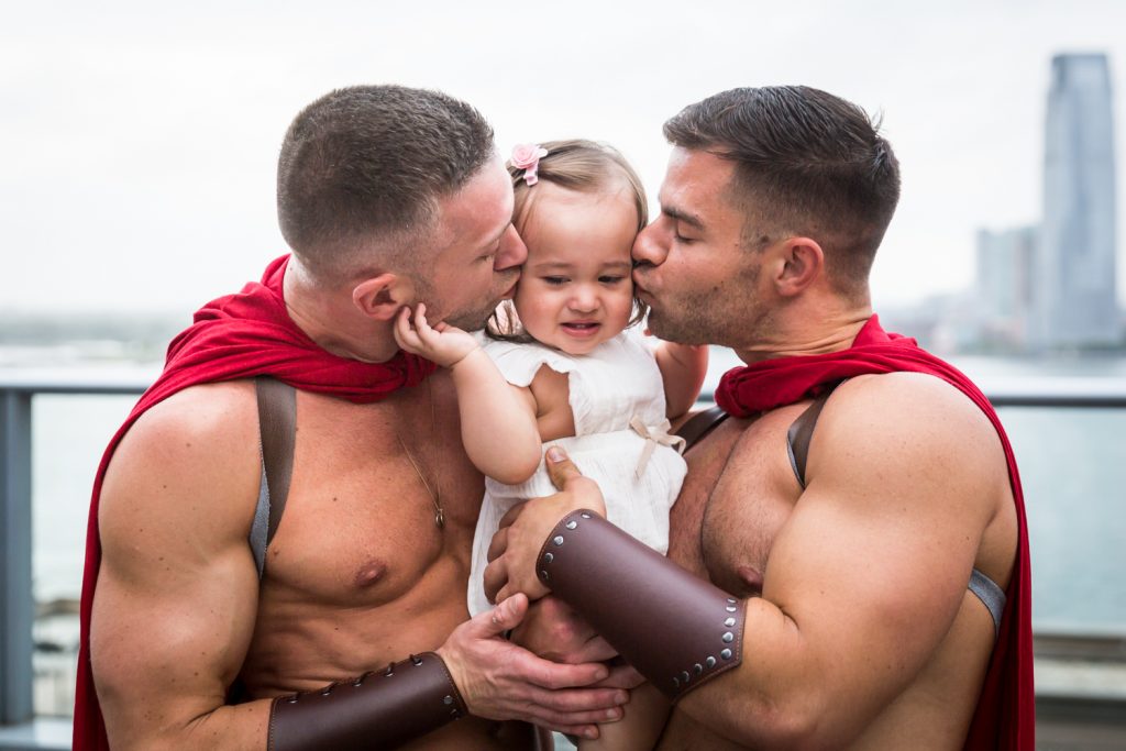 Birthday party photography of two men dressed as gladiators kissing little girl on both cheeks