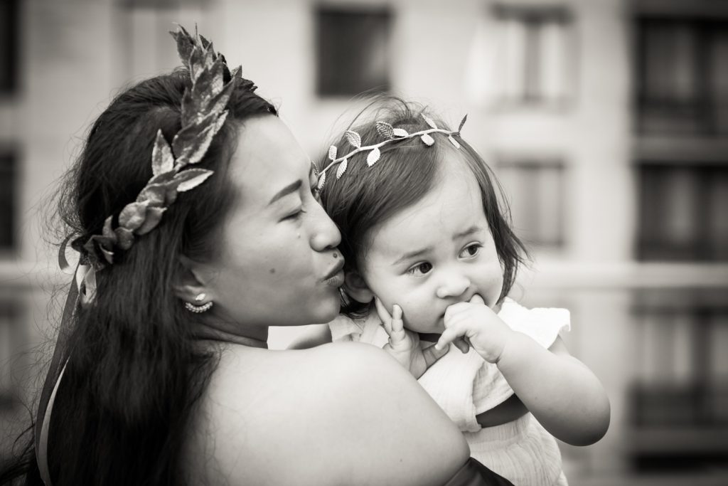 Black and white photo of mother holding little girl with both wearing laurel crowns
