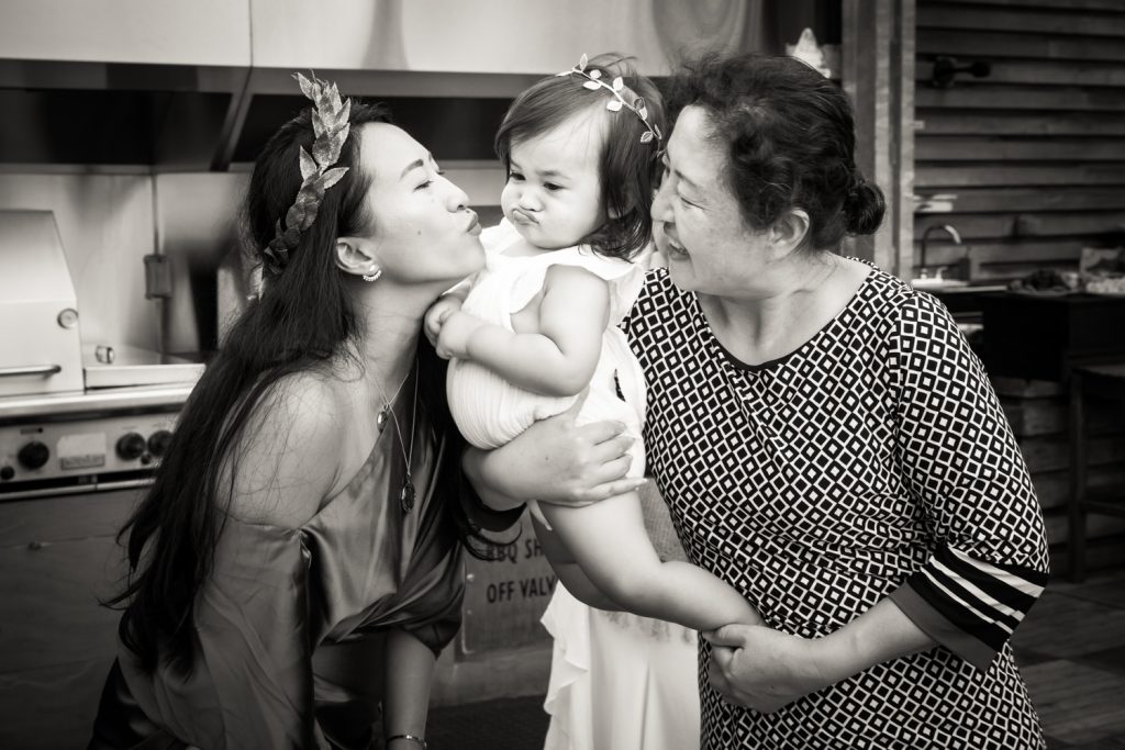 Black and white photo of mother kissing little girl held by nanny