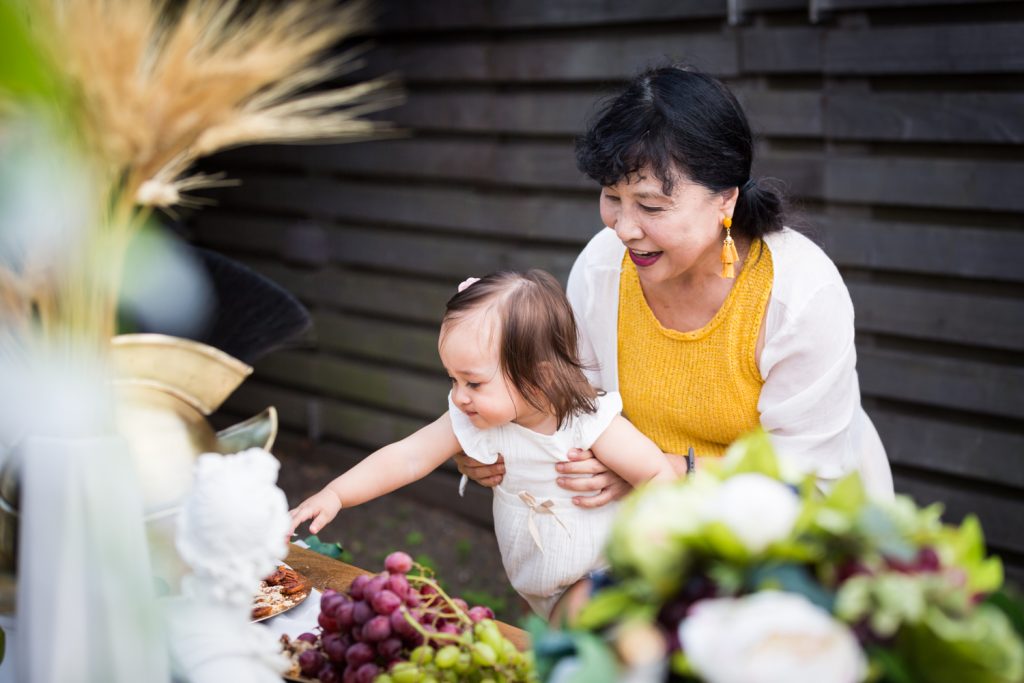 Birthday party photography of grandmother holding baby in front of food buffet