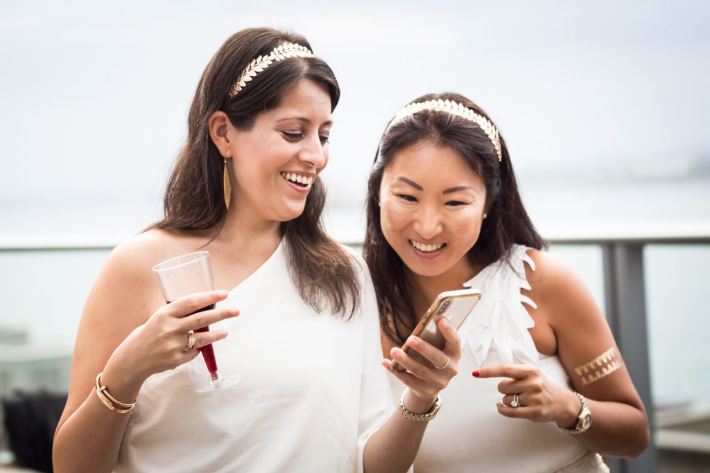 Two women dressed in toga outfits looking at cell phone