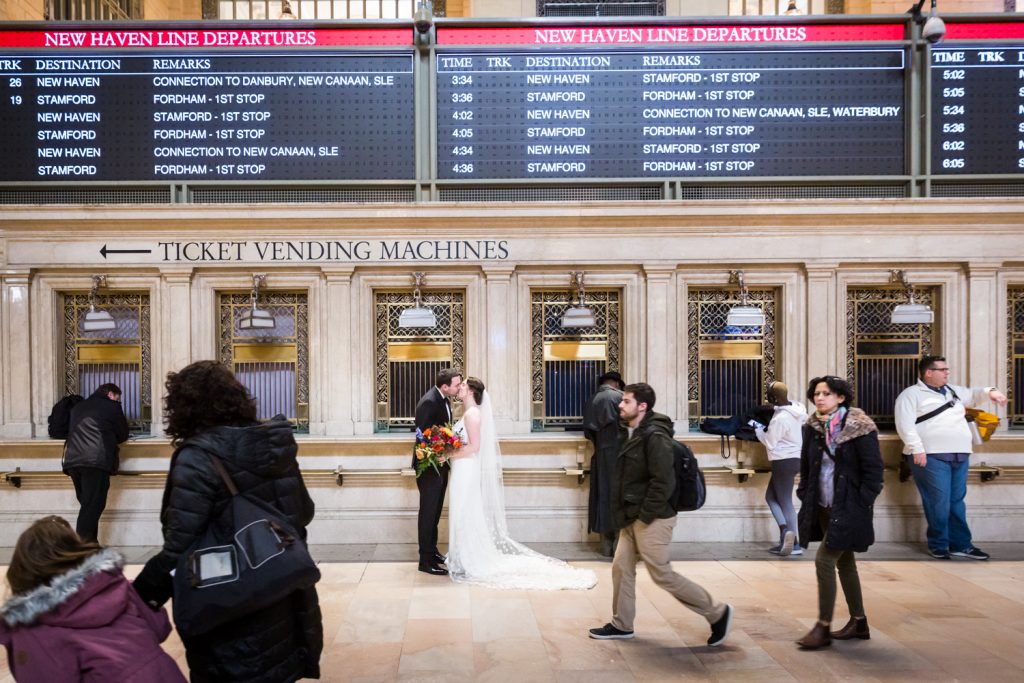 Bride and groom in front of ticket windows in Grand Central Terminal at a Water Club wedding