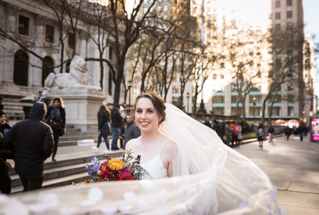 Bride with flowing veil in front of New York Public Library