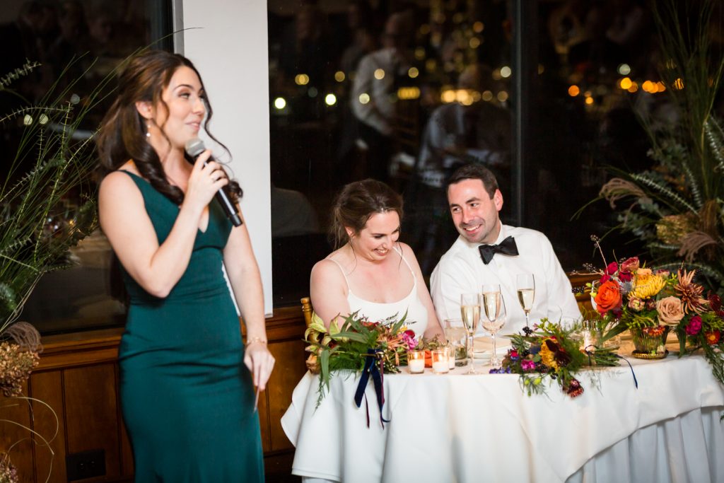 Maid of honor making speech in front of bride and groom