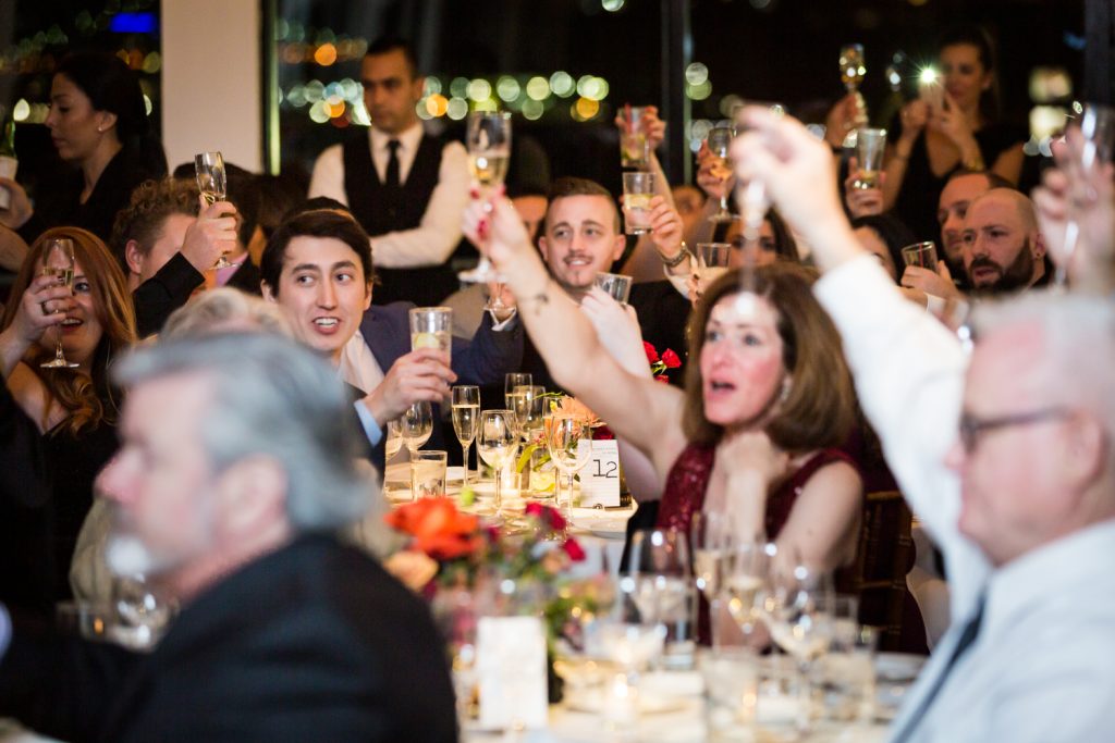 Guests toasting with raised glasses at a Water Club wedding