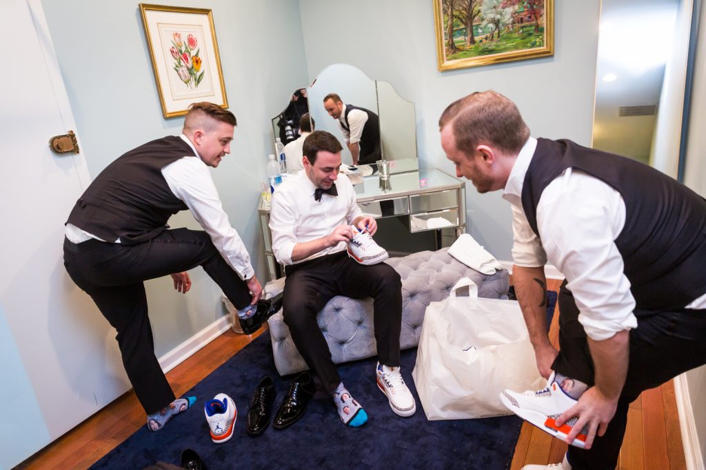 Groom and groomsmen changing into tennis shoes at a Water Club wedding