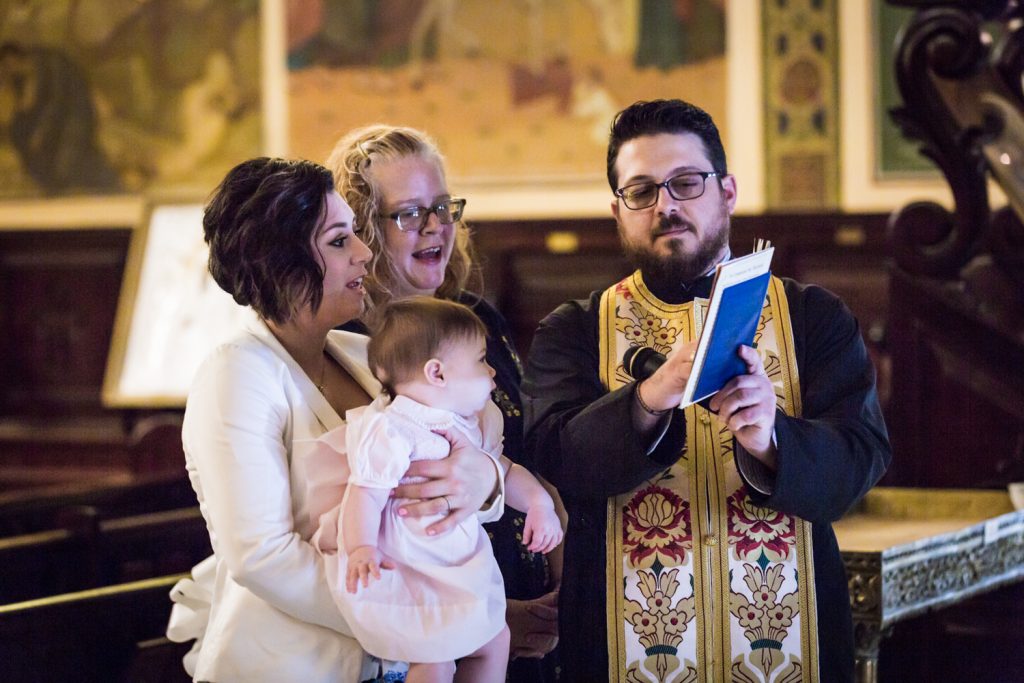 Greek orthodox baptism photos of priest reading to baby and godparents