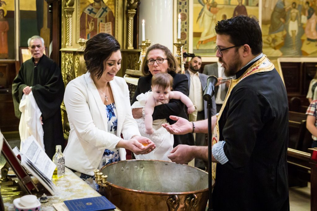 Greek orthodox baptism photos of priest pouring oil into hands of godmother