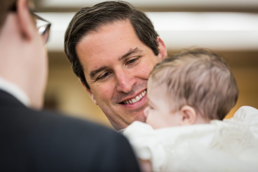 Man smiling at baby at Greek orthodox baptism reception