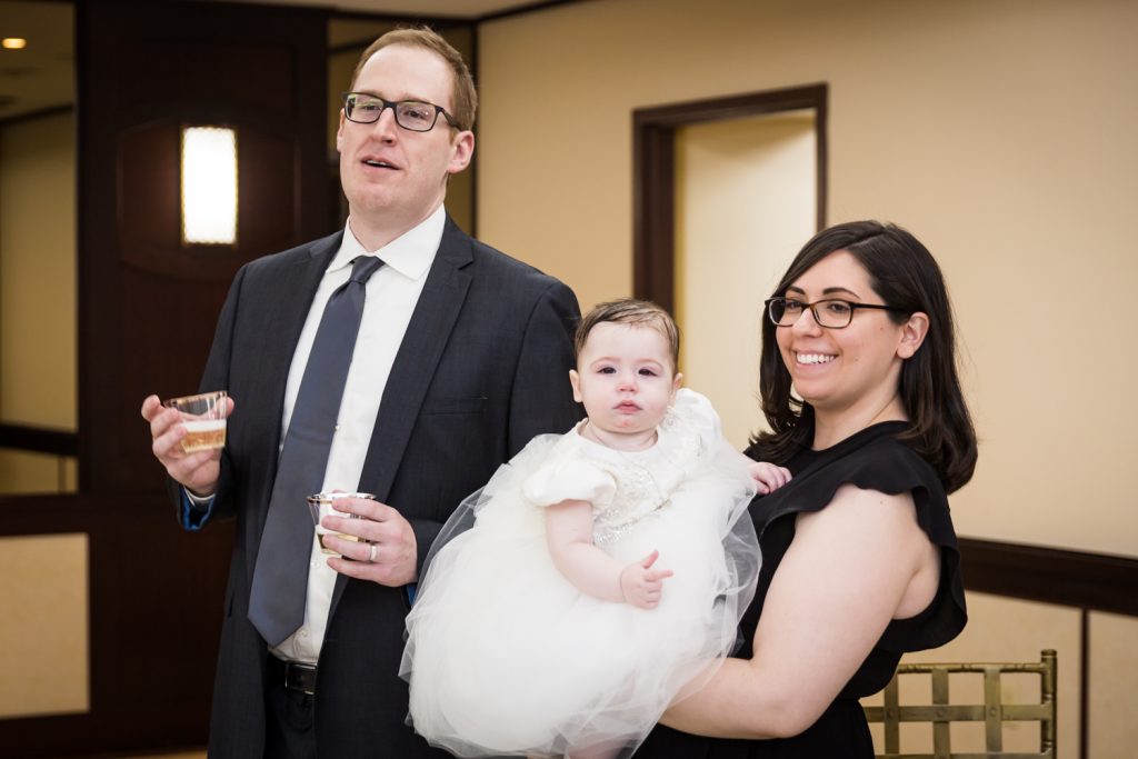 Parents holding baby and giving speech at Greek orthodox baptism reception