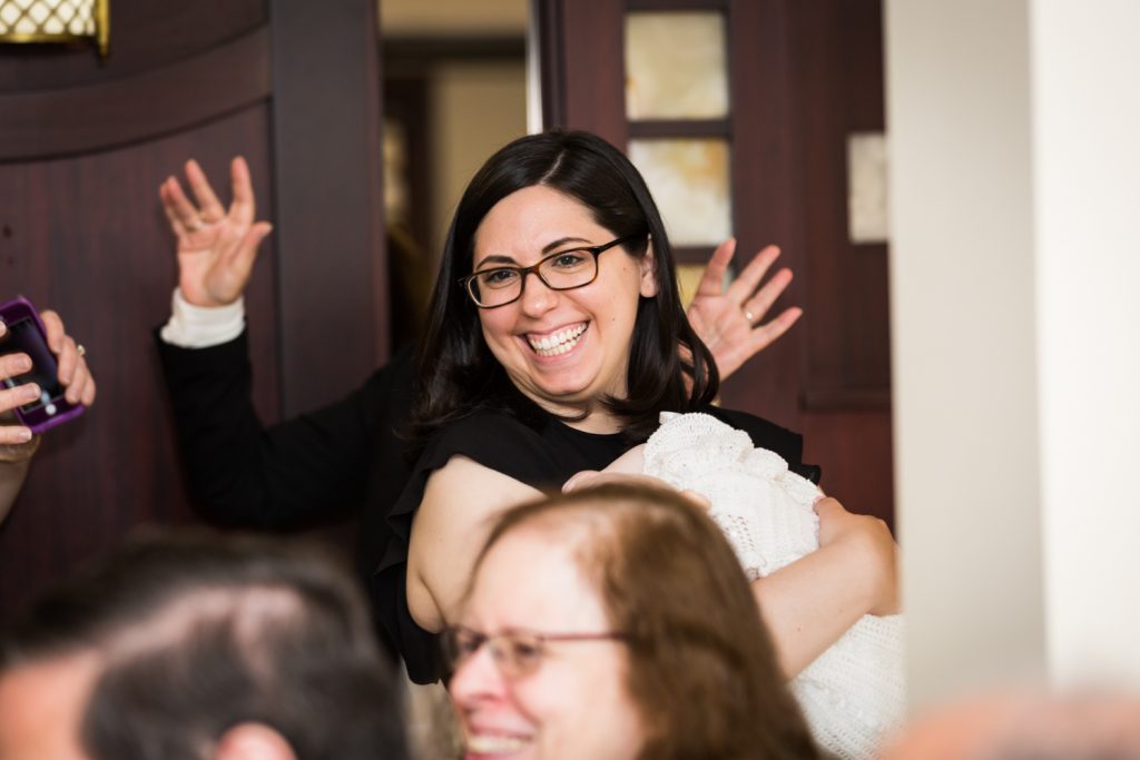 Mother holding baby and smiling at Greek orthodox baptism reception