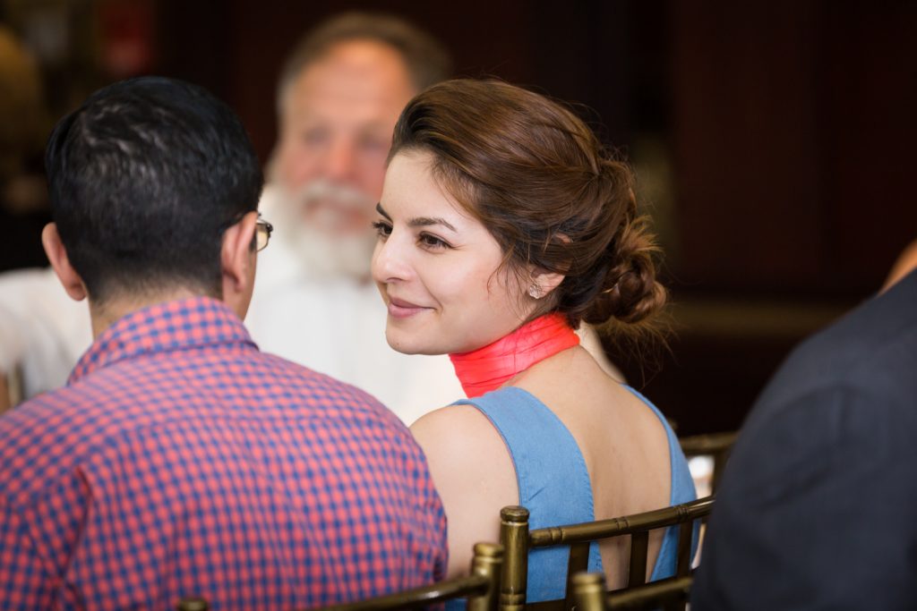 Female guest with hair in bun smiling at Greek orthodox baptism reception