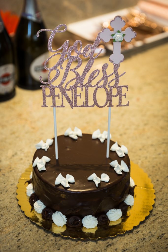 Chocolate cake with topper that says 'God Bless Penelope'