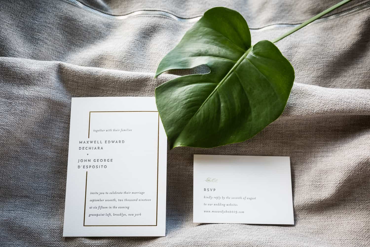 Wedding invitation and green leaf on grey pillow