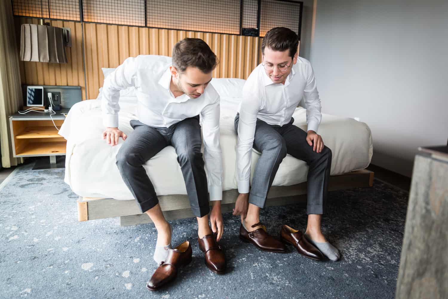 Greenpoint Loft wedding photos of two grooms putting on shoes while sitting on bed