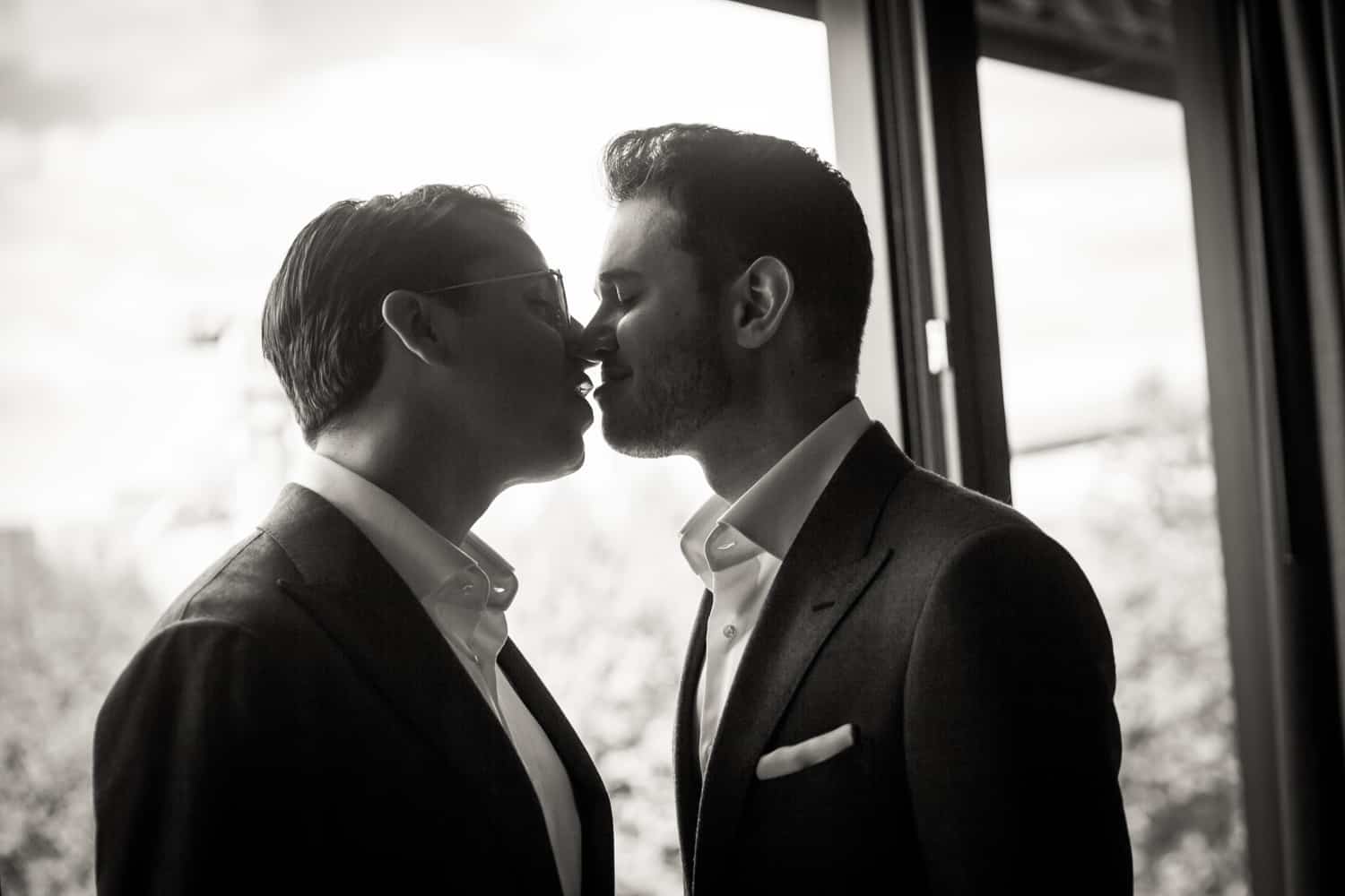 Black and white photo of two grooms kissing