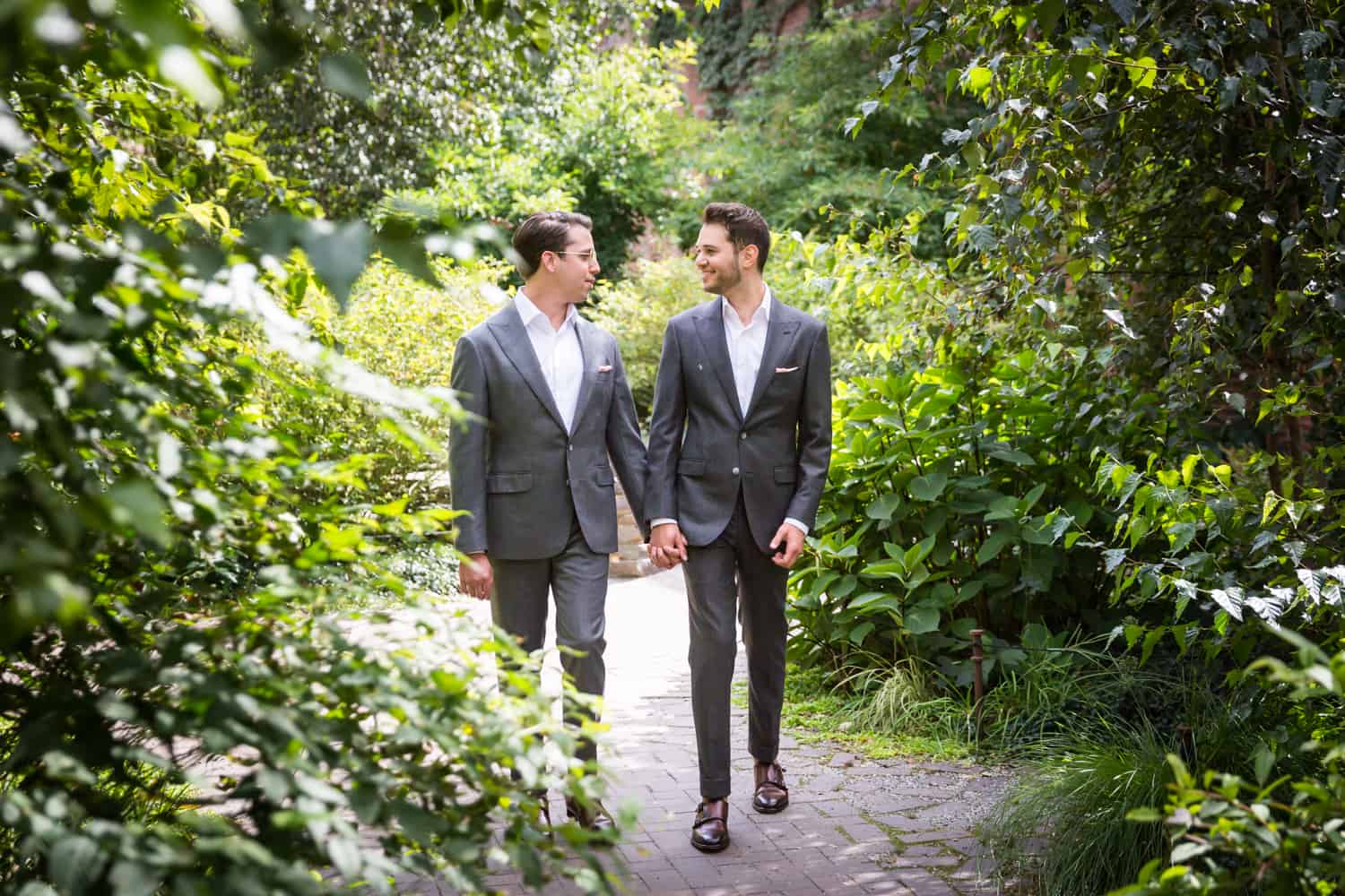 Greenpoint Loft wedding photos of two grooms walking through garden at St. Ann's Warehouse