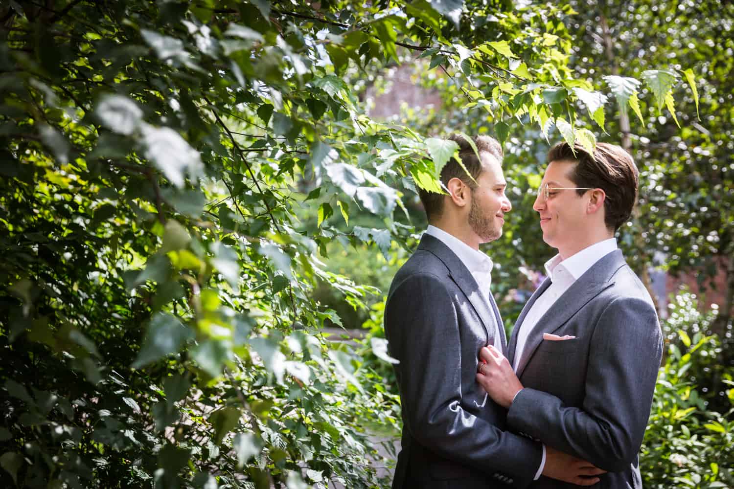 Greenpoint Loft wedding photos of two grooms in bushes at St. Ann's Warehouse