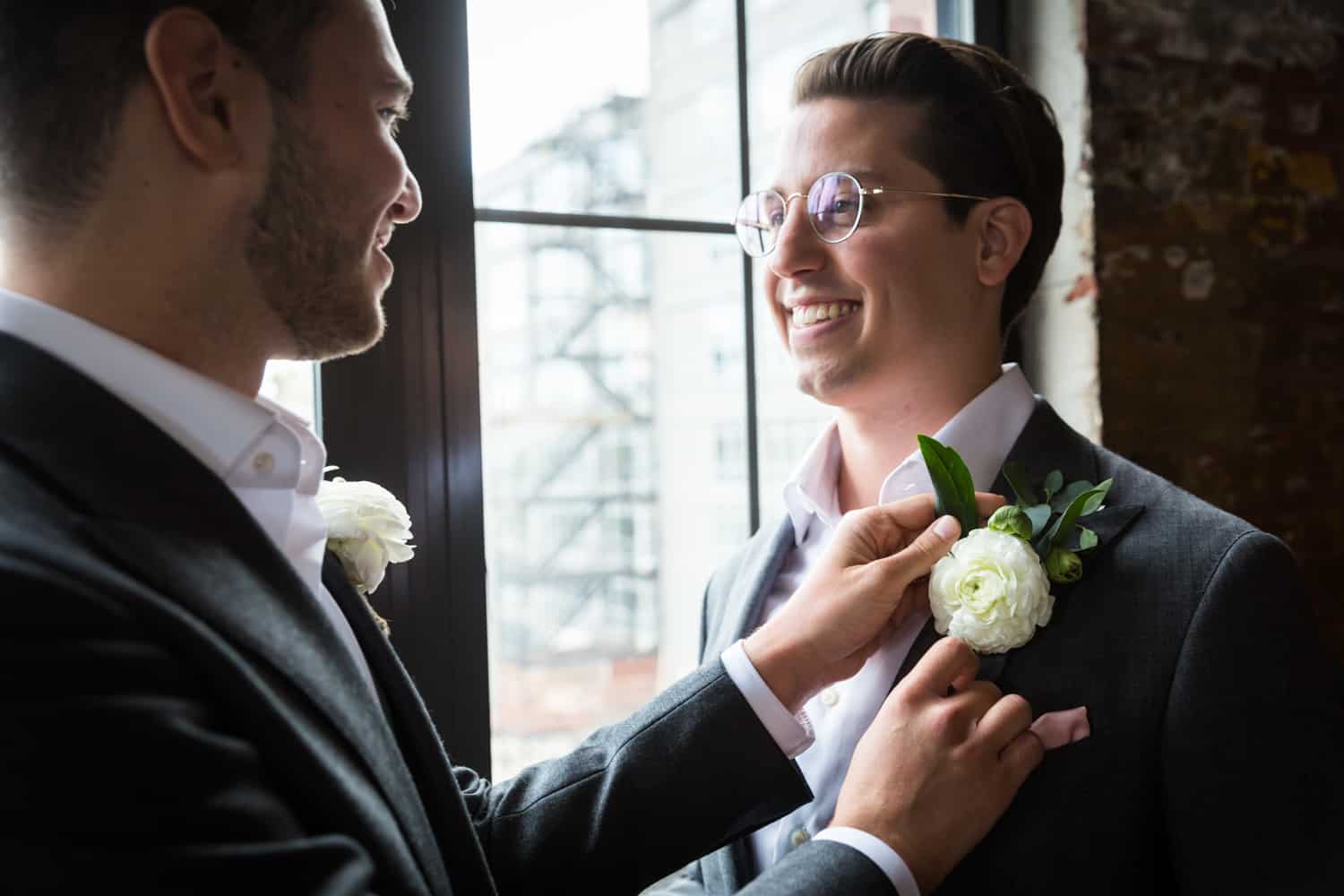Greenpoint Loft wedding photos of groom helping other groom with his boutonniere