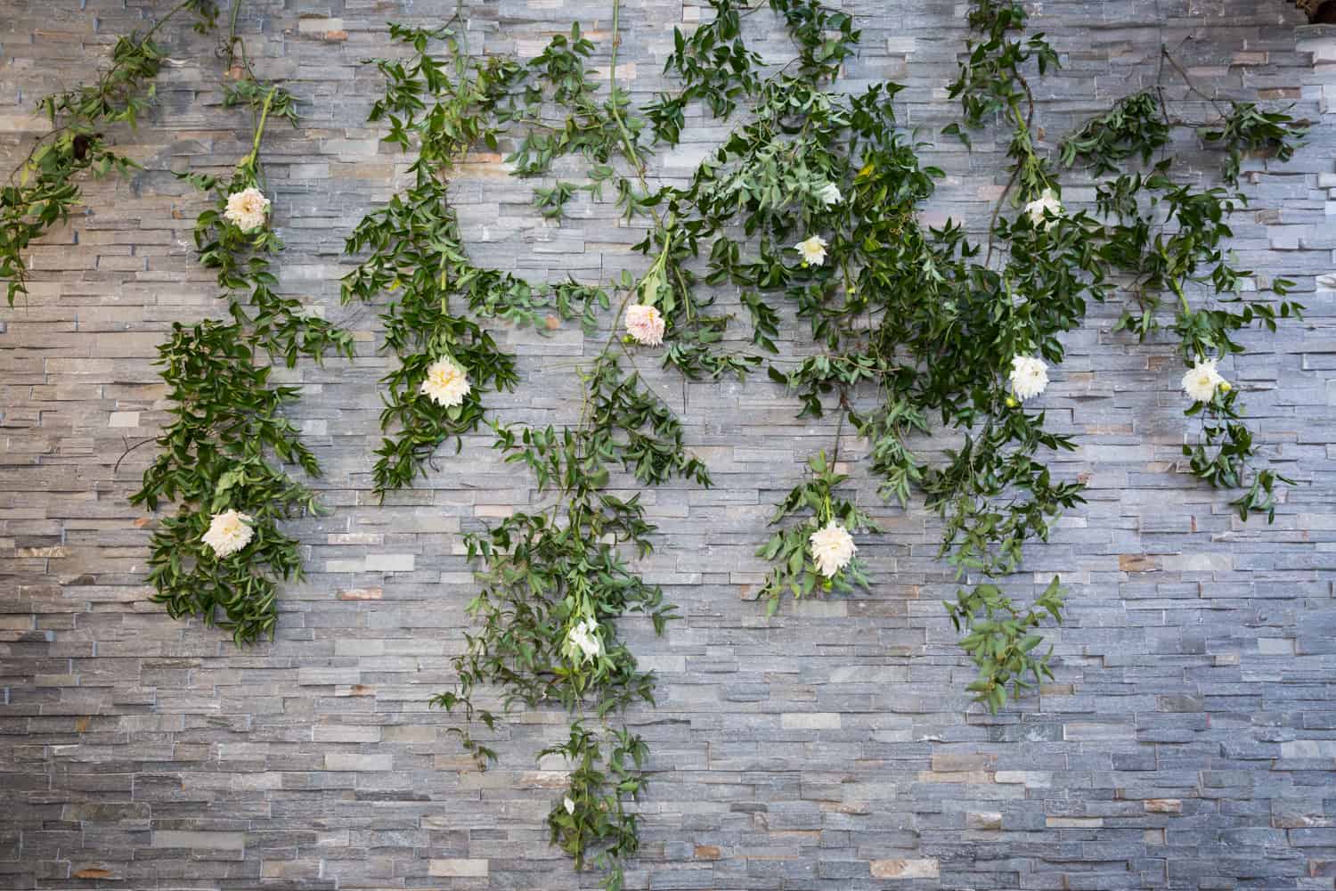 Grey brick wall covered with vines and flowers