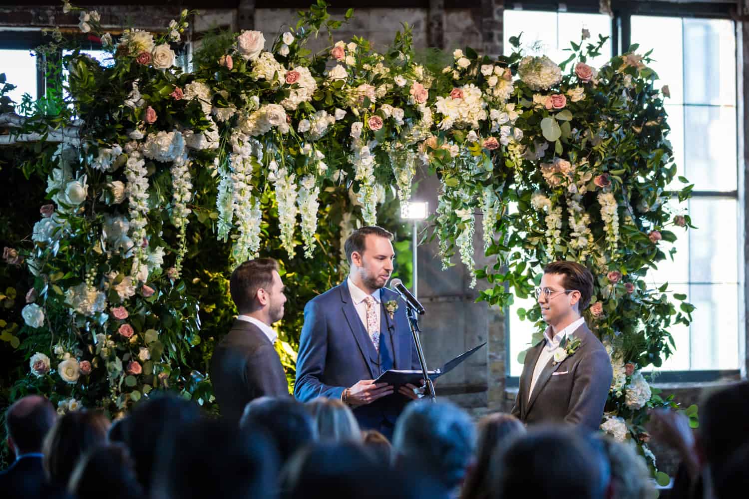 Greenpoint Loft wedding photos of gay wedding ceremony under floral altarpiece