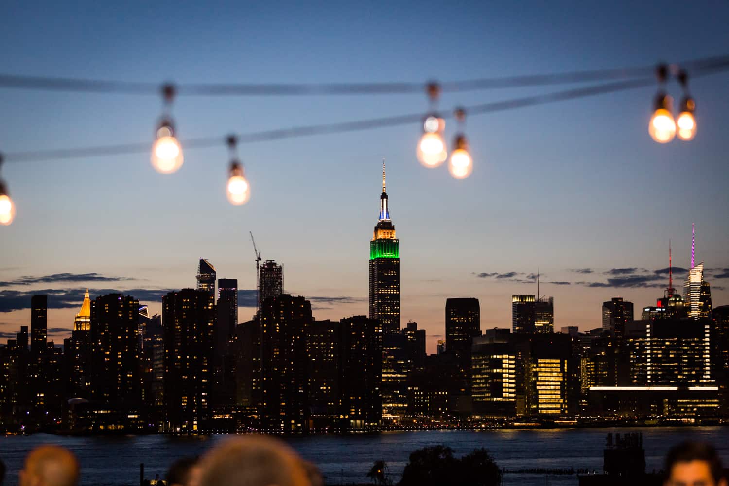 Rooftop view of Empire State Building with strings of lights at dusk