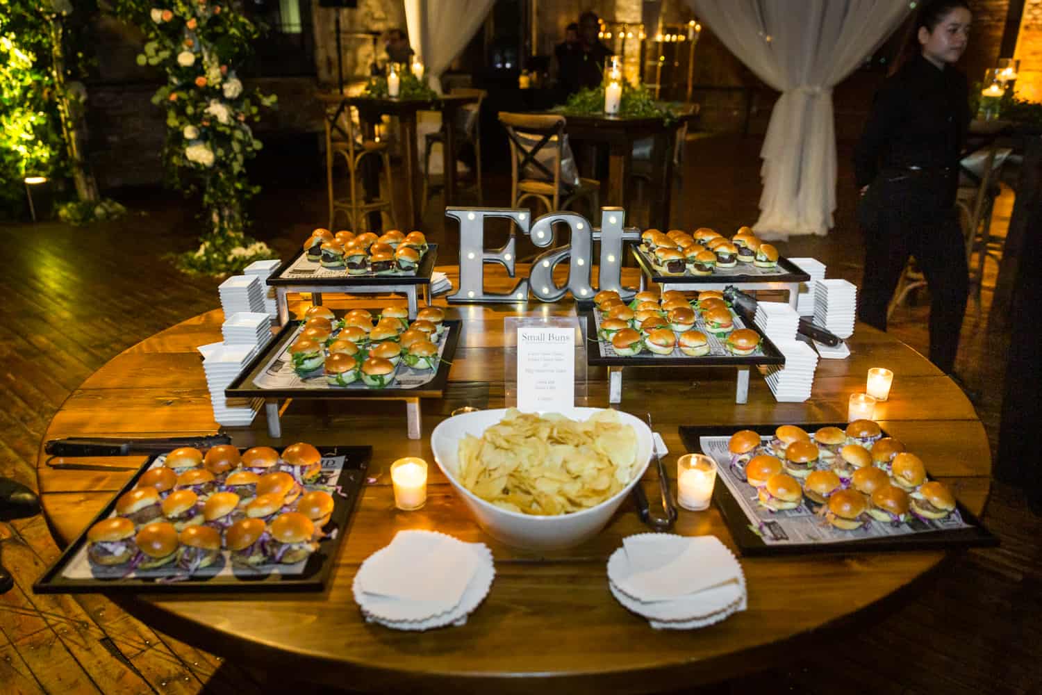 Table filled with plates of mini burgers and 'Eat' sign
