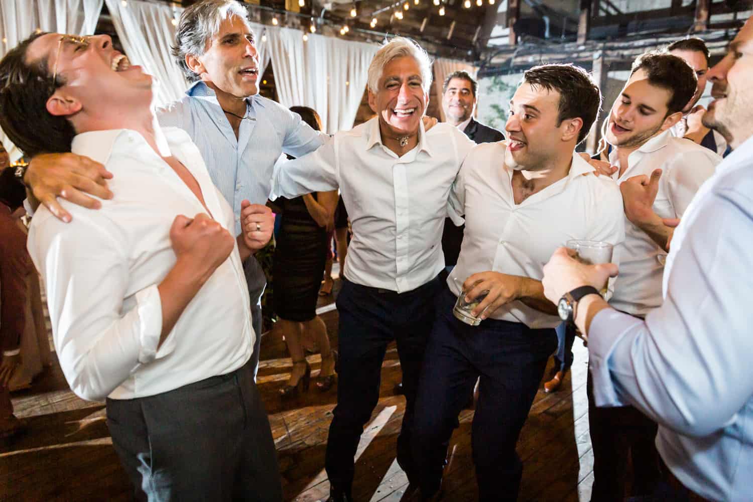 Group of male guests dancing with two grooms at Greenpoint Loft wedding