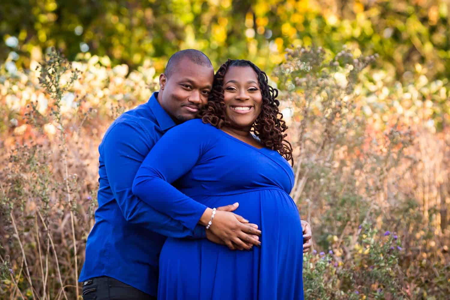 African American couple hugging in Forest Park for an article on maternity photo shoot ideas