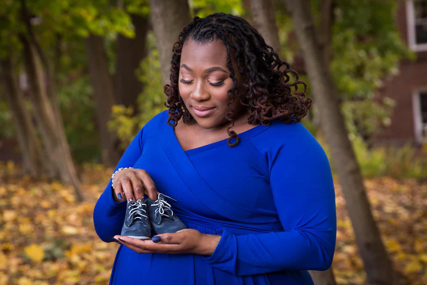 African American pregnant woman holding pair of baby shoes