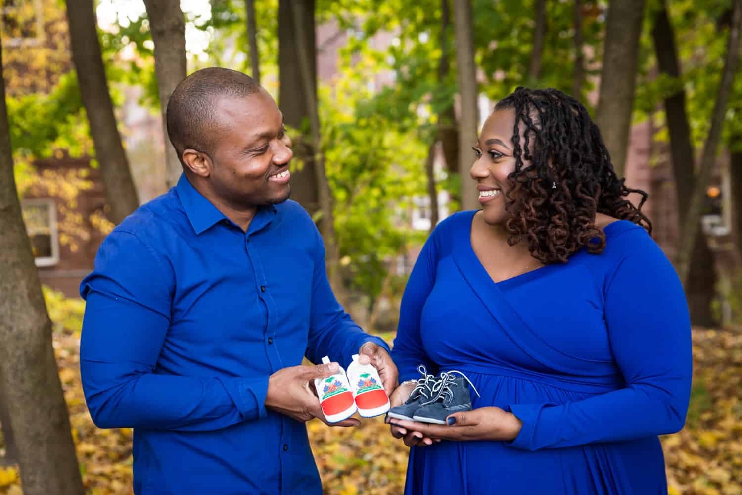 African American expecting couple each holding pair of baby shoes