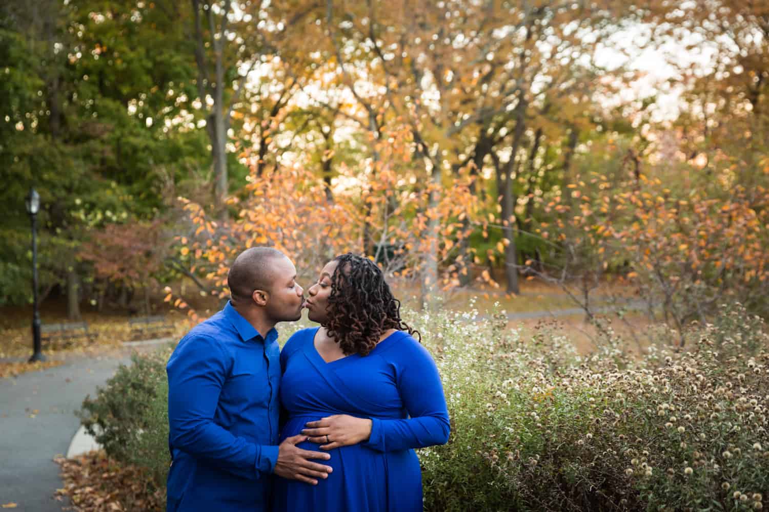 African American couple kissing in Forest Park for an article on maternity photo shoot ideas