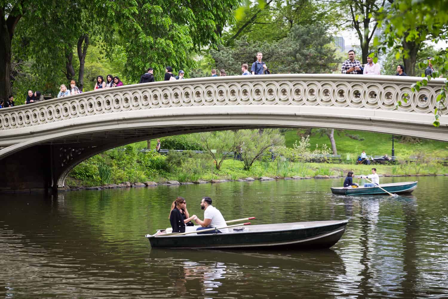 Man proposing to woman under Bow Bridge at a surprise proposal on Central Park Lake