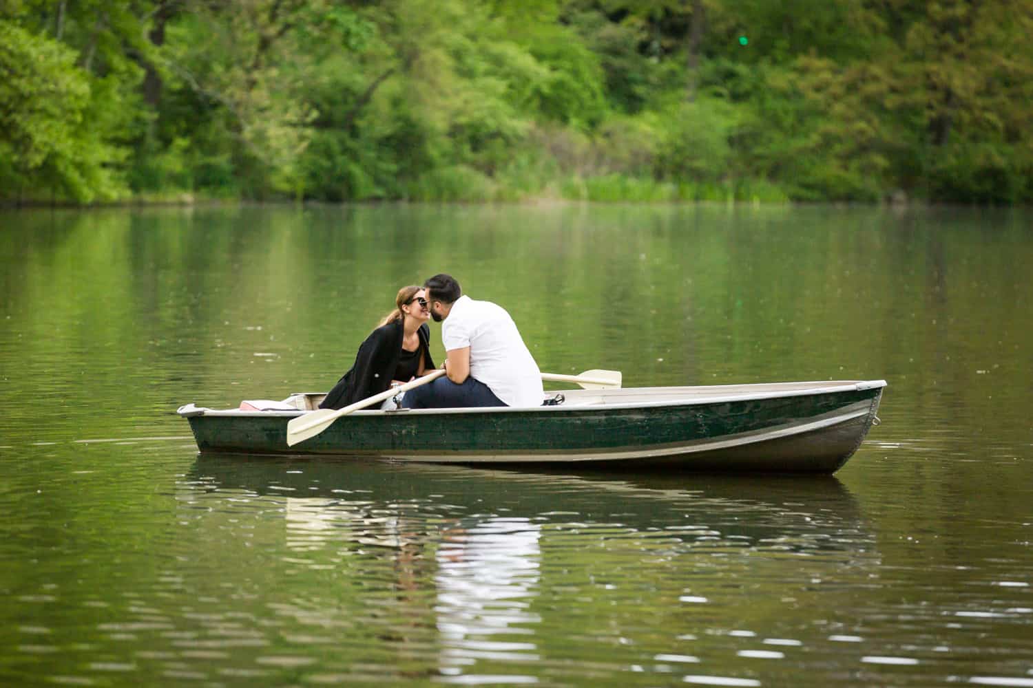 Couple kissing in boat at a surprise proposal on Central Park Lake