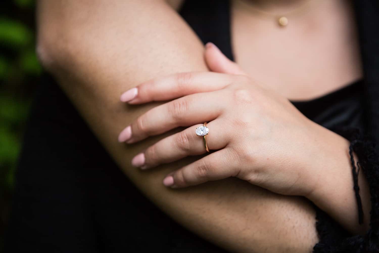Close up of woman's hand with engagement ring resting on man's arm