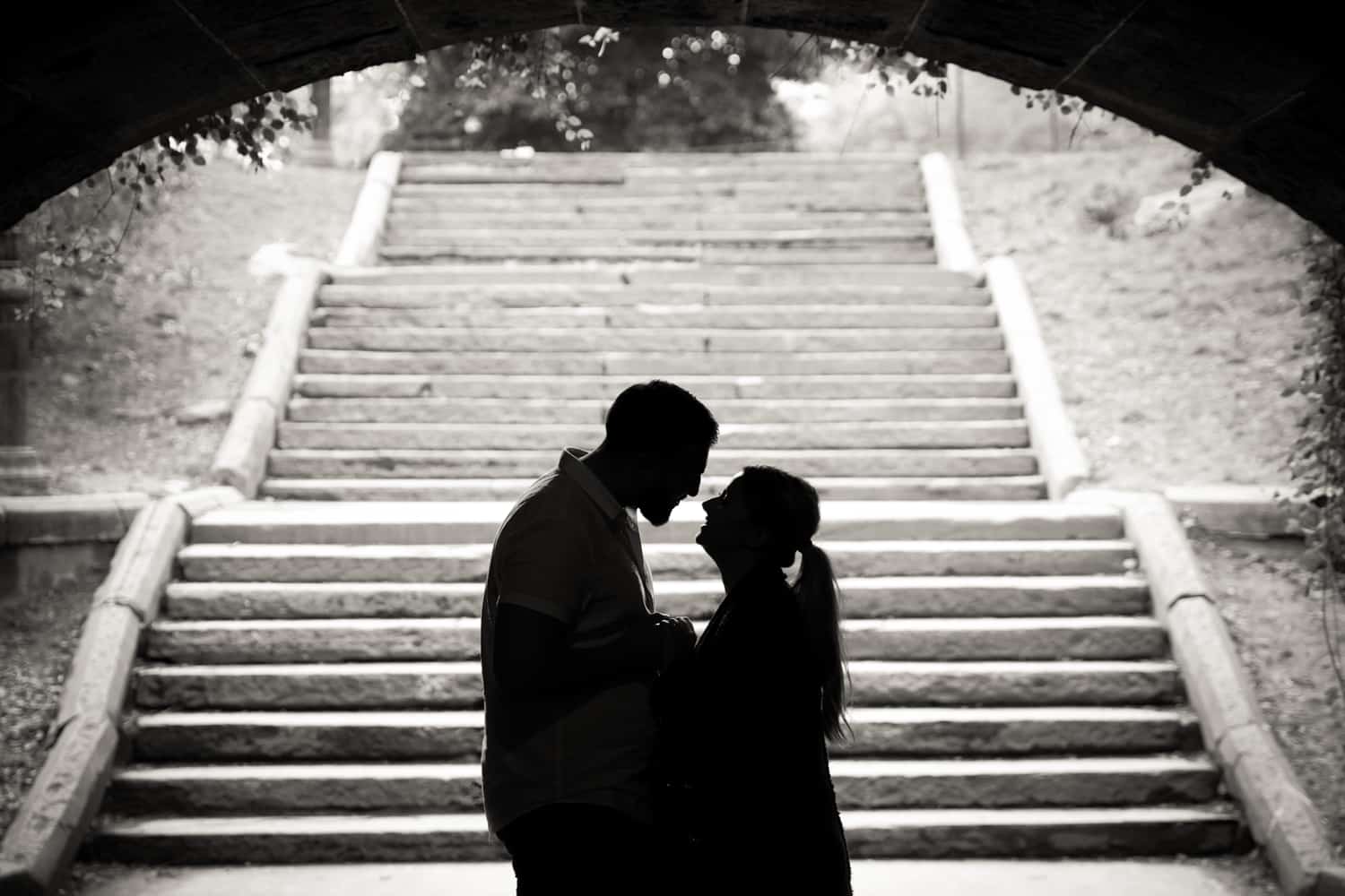 Black and white photo of backlit couple standing in front of staircase