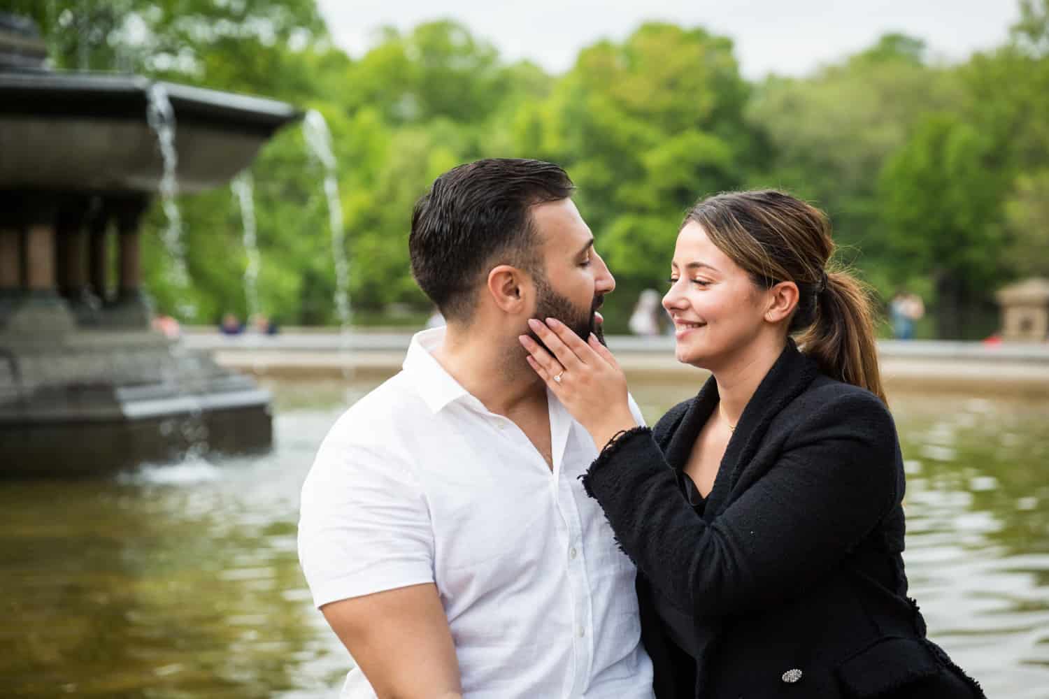 Woman touching man's cheek in front of Bethesda Fountain