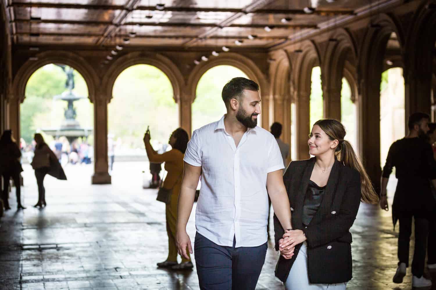 Couple walking hand-in-hand through Bethesda Terrace in Central Park