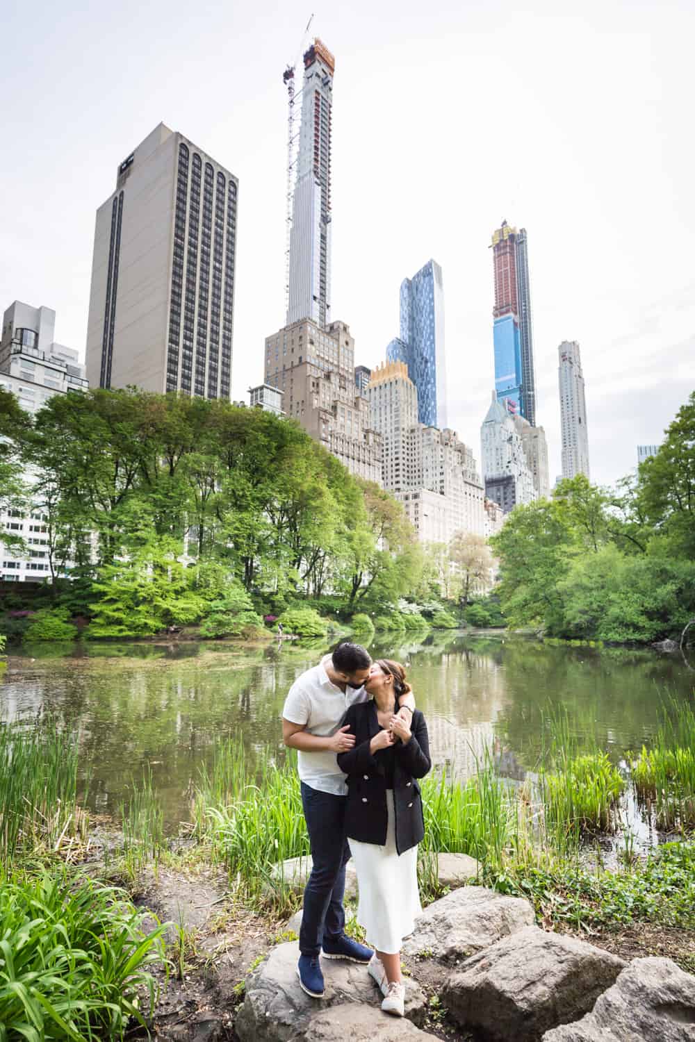Couple kissing in front of Central Park pond