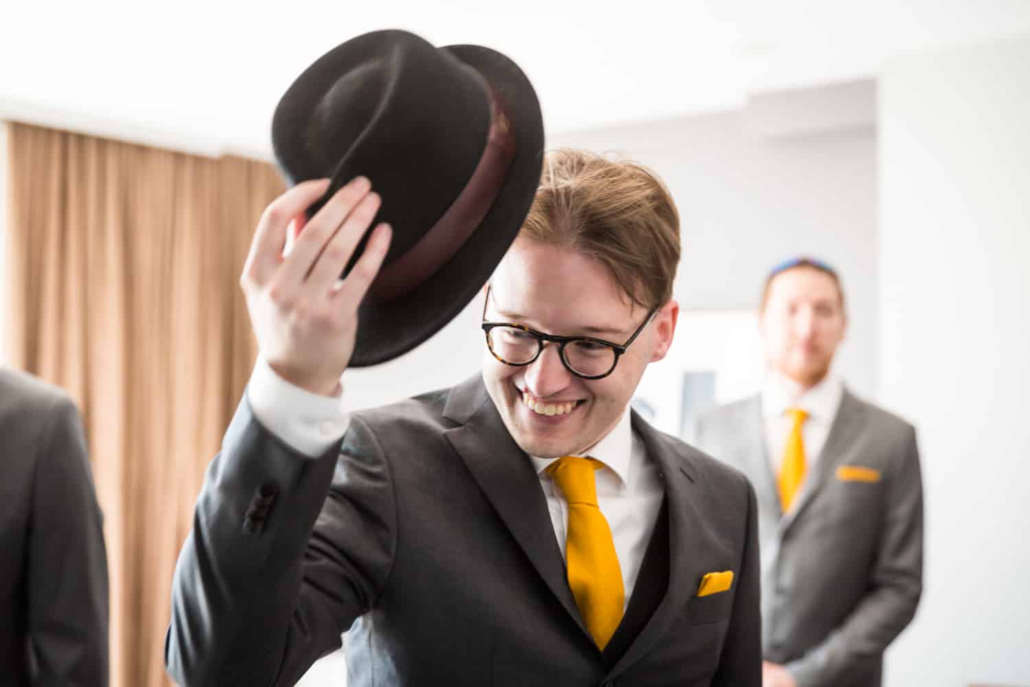 Groom pulling off hat in hotel room