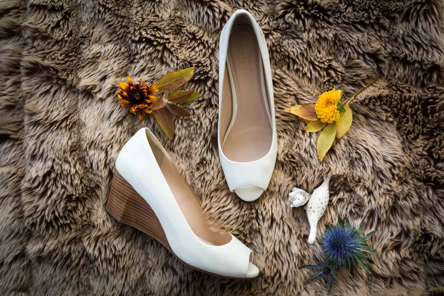 Bride's white wedge heels flowers and jewelry on furry rug
