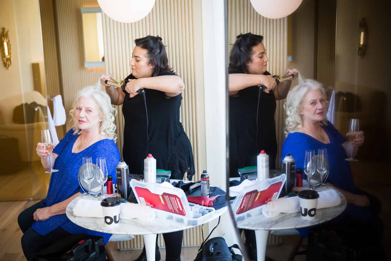 Mother of bride getting hair fixed with reflection in wall