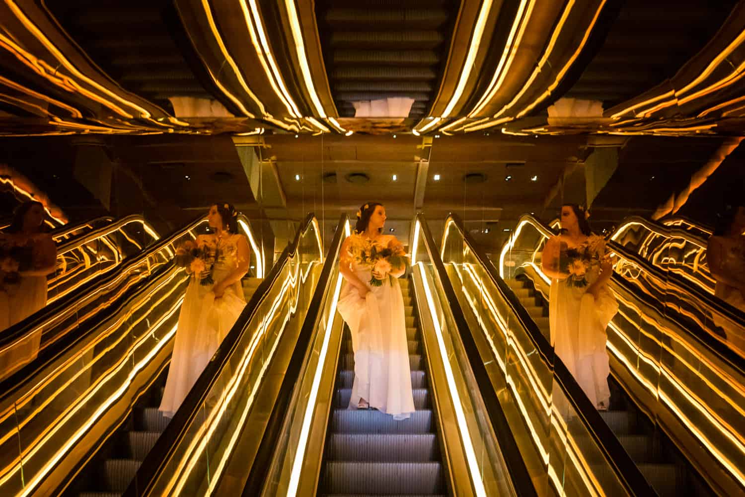 Bride coming down neon-lit escalator