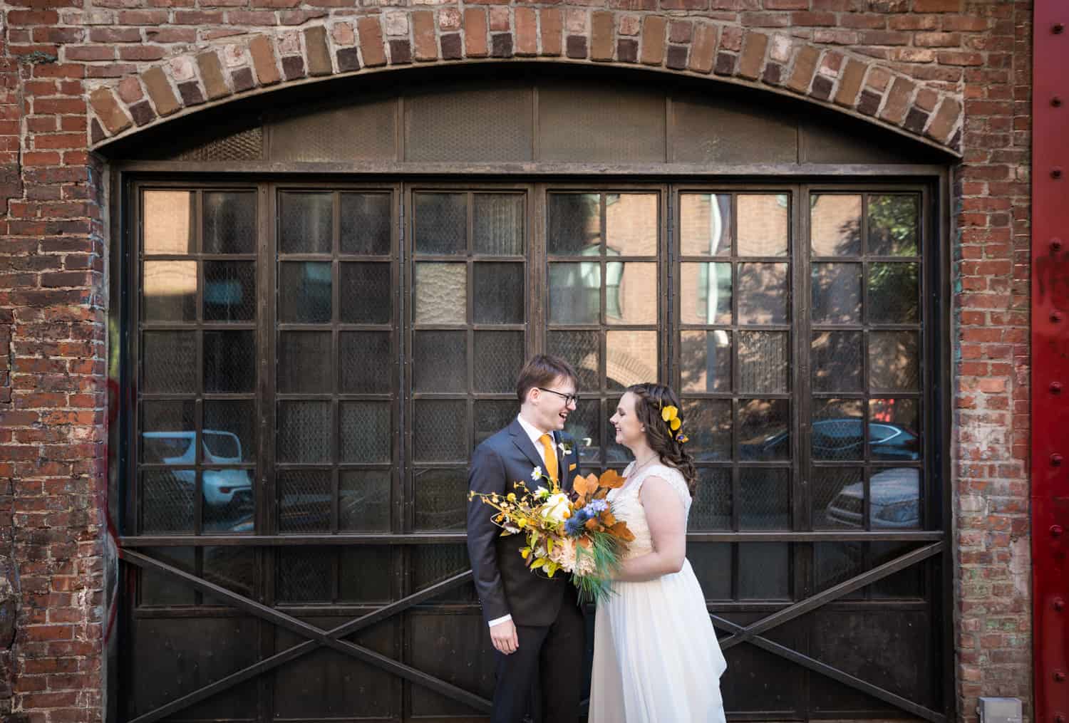 Bride and groom in front of arched window for an article on Covid-19 wedding planning
